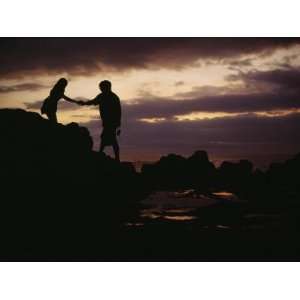  A Man with a Camera Helps a Woman Down Rocks Near Tanah 